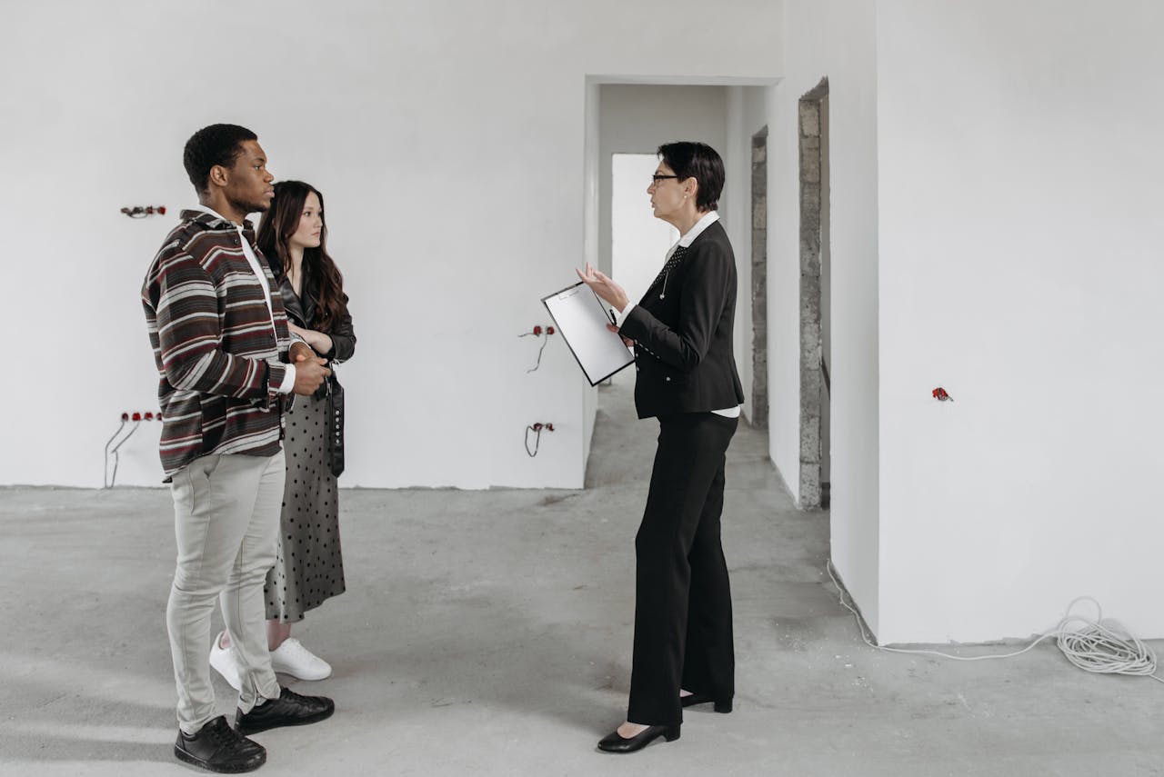 services-02 Real estate agent showing a house to a couple in a newly built home interior.